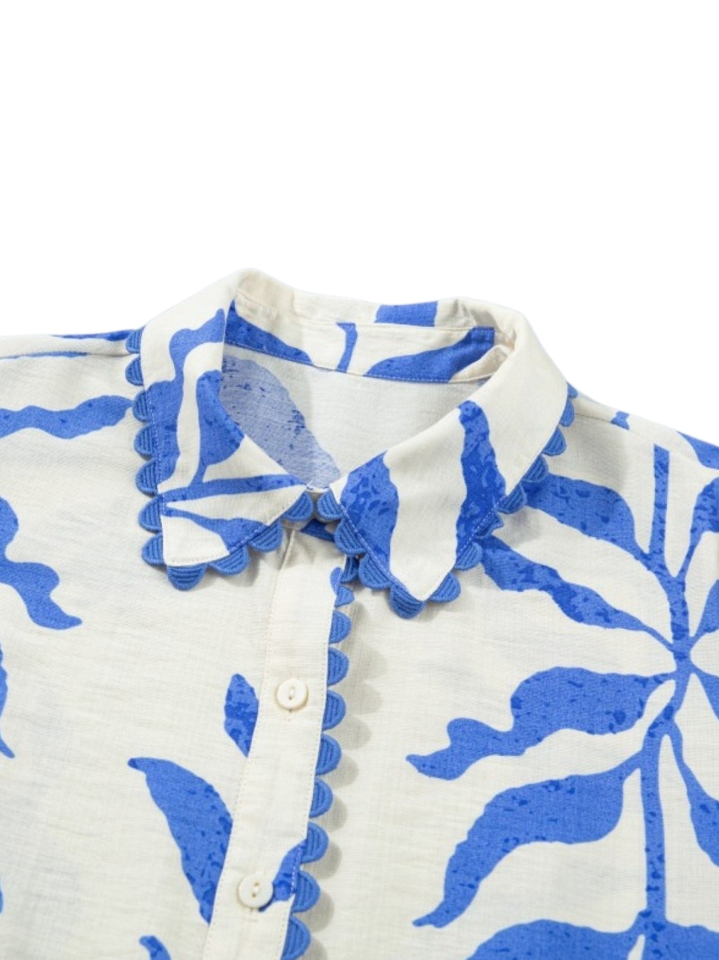 Close-up of a white button-front shirt with a blue floral print and scalloped blue trim along the collar and placket.