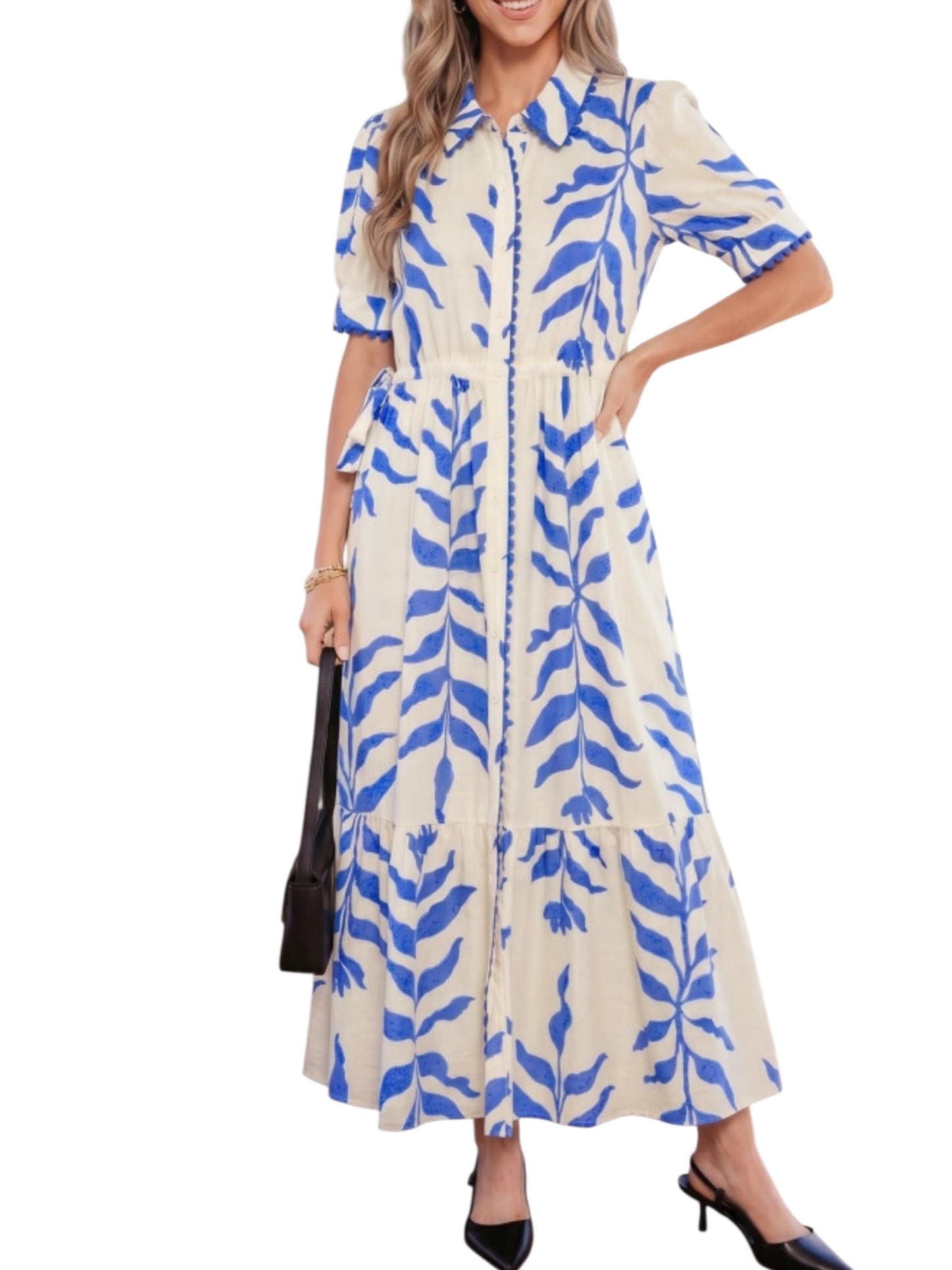 A woman models a short-sleeve collared midi dress with a blue leaf pattern on a cream background, holding a black handbag against a plain white background.
