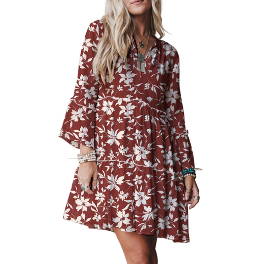 Woman wearing a floral dress with bell sleeves on a plain background