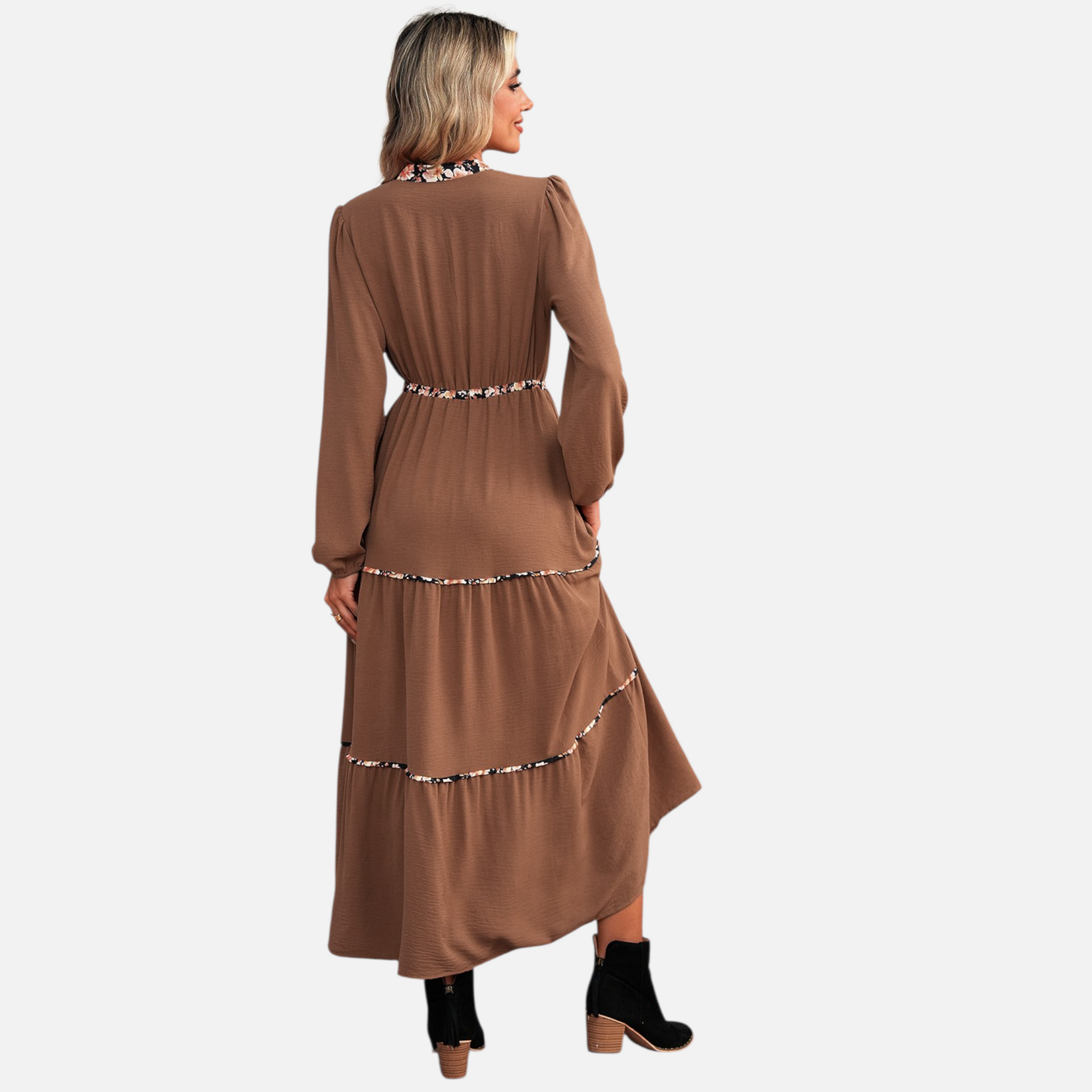 Rear view of a model wearing a brown tiered maxi dress with floral patchwork details, highlighting the flowy silhouette and long sleeves.