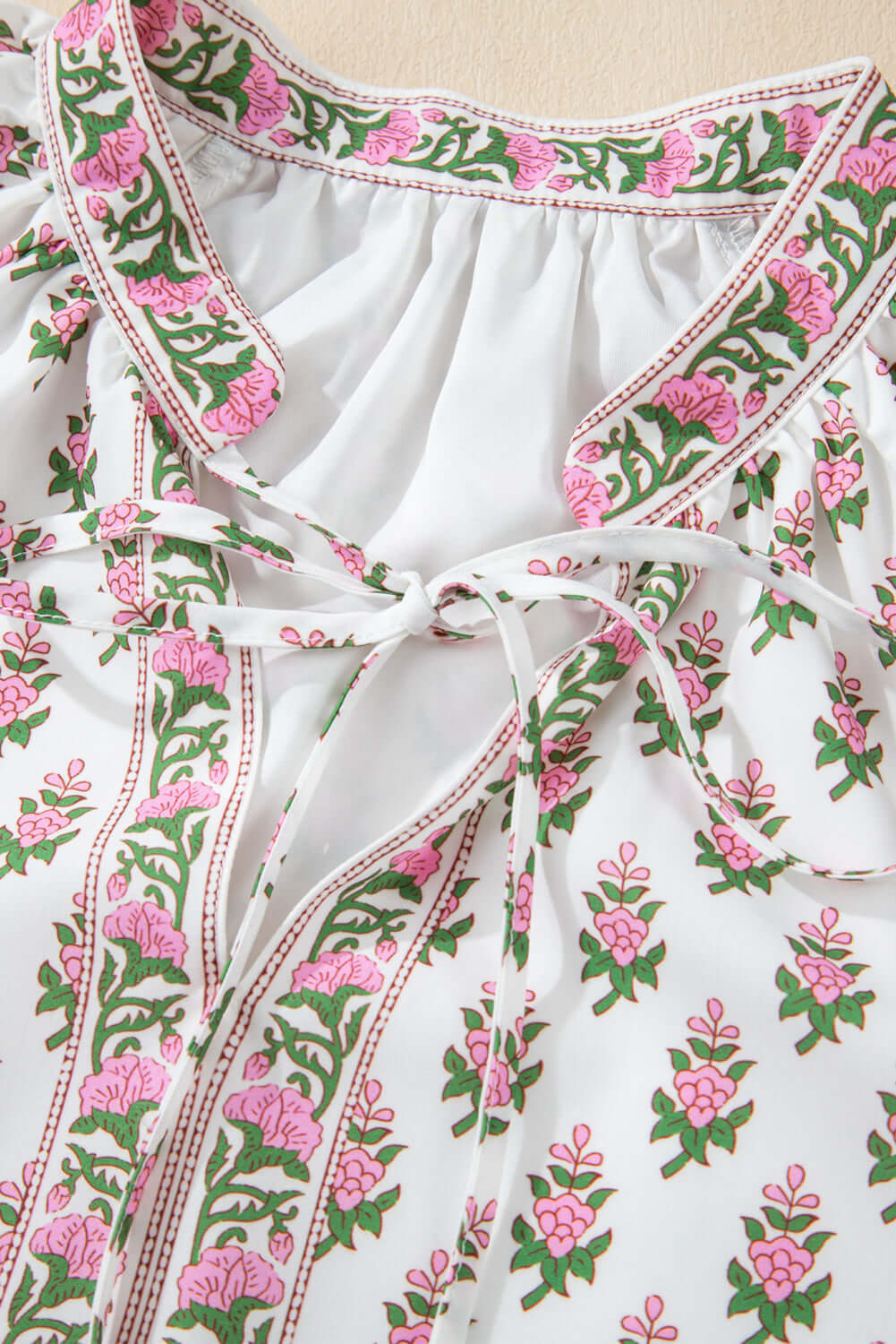 Close-up of pink floral dress with adjustable drawstring waist and lightweight polyester fabric.