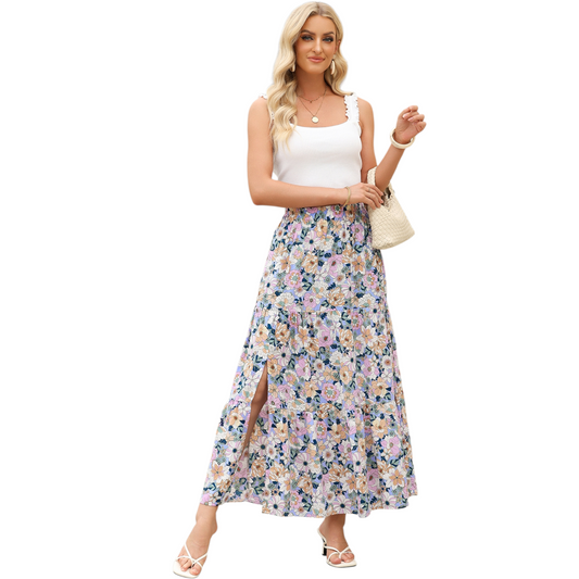 A woman wearing a lightweight, tiered floral maxi skirt in shades of purple and pink with a high side split and elasticated waist.