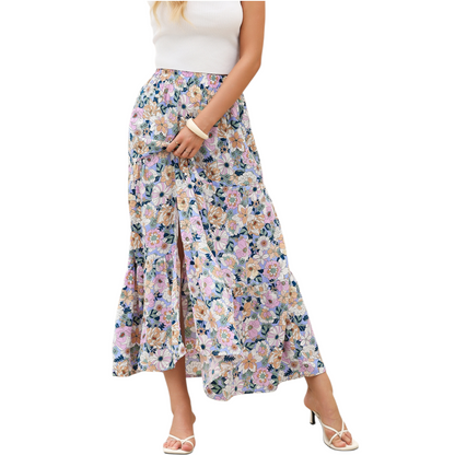 A woman wearing a lightweight, tiered floral maxi skirt in shades of purple and pink with a high side split and elasticated waist.