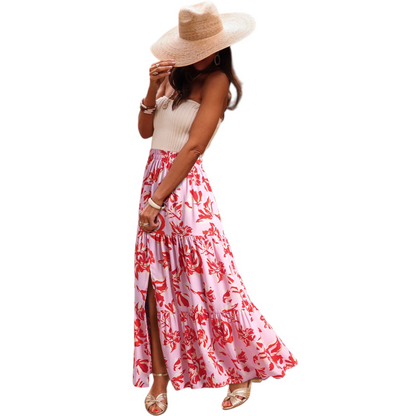 A woman wearing a lightweight, tiered floral maxi skirt in shades of red and pink with a high side split and elasticated waist.