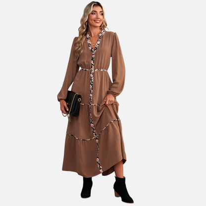 Full-body view of a model in a brown bohemian maxi dress with tiered skirt and floral-accented trim, perfect for elevated daywear.