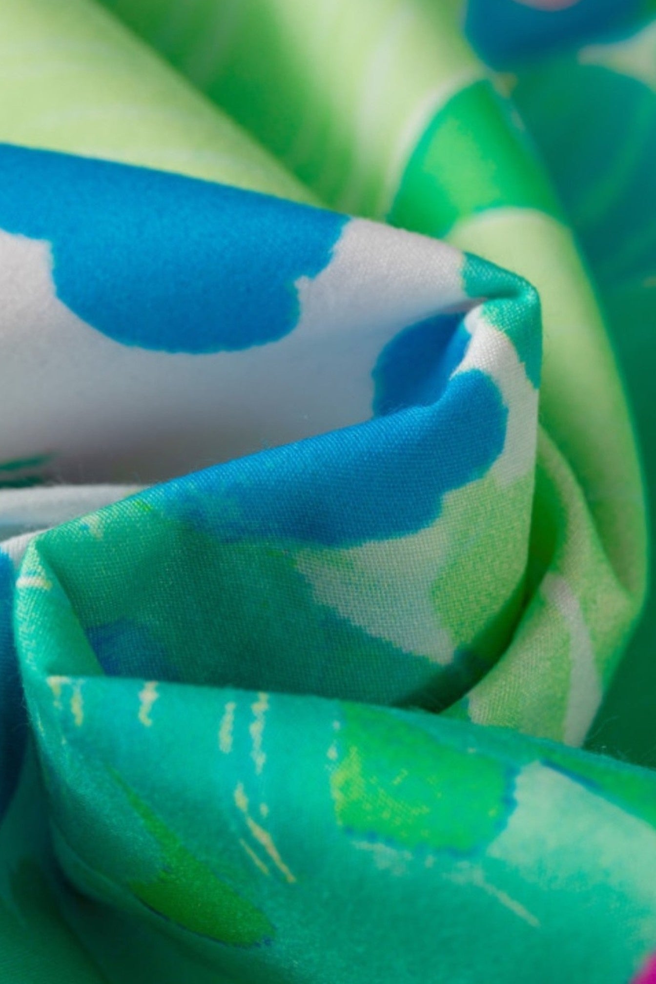 A close-up of a draped fabric with a colorful abstract print featuring bright blue, green, and white shapes.
