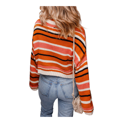 Person wearing a colorful striped sweater and jeans on a white background