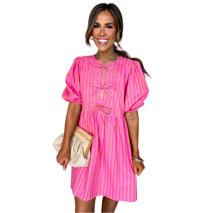 Front view of a pink and orange striped mini dress featuring three decorative front bows and a round neckline.