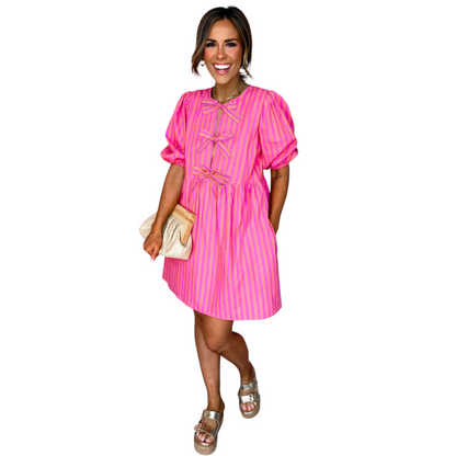 Front view of a pink and orange striped mini dress featuring three decorative front bows and a round neckline.