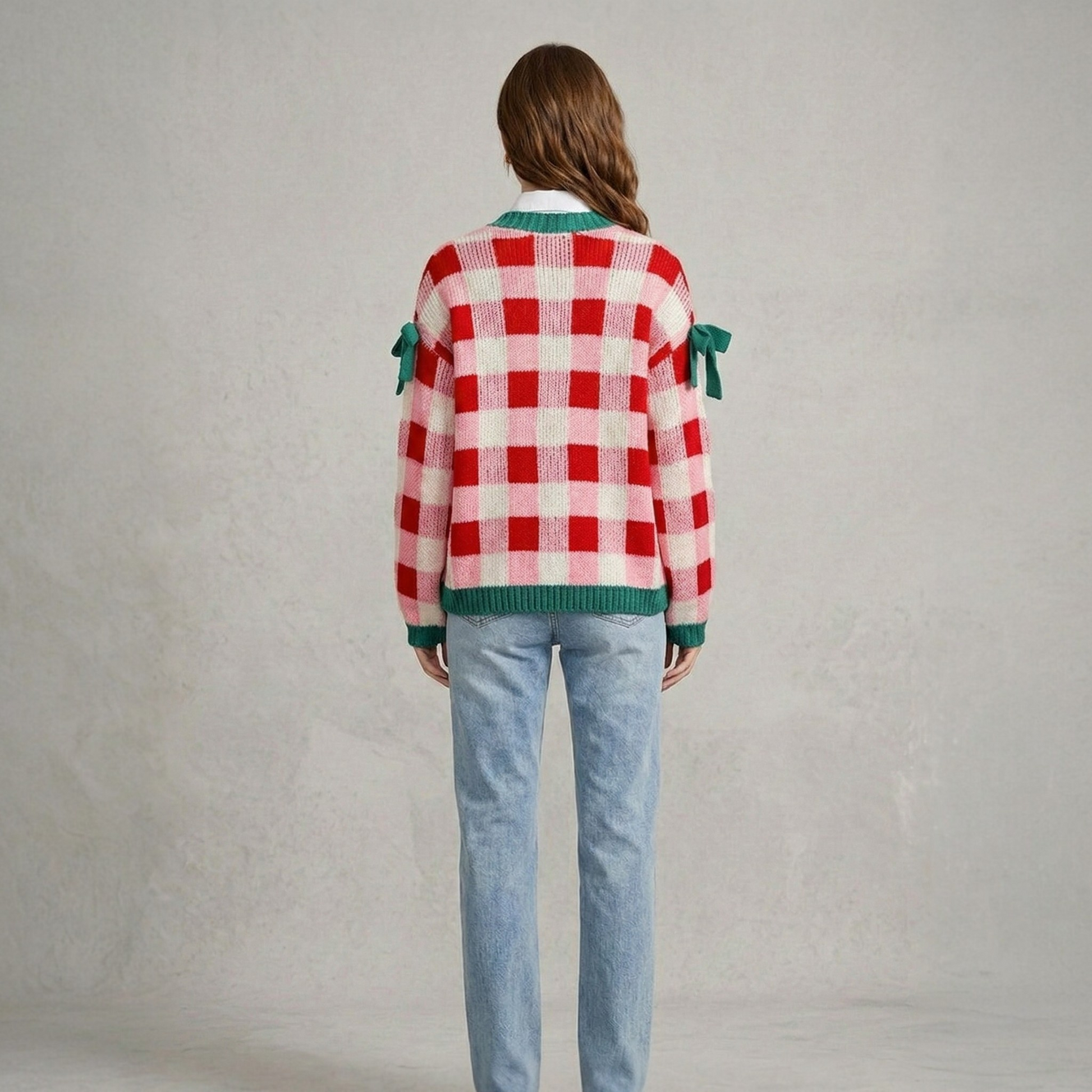 Back view of a model wearing a pink and red checkered open-front knit cardigan, highlighting the relaxed fit and green knitted hem.