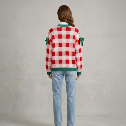 Back view of a model wearing a pink and red checkered open-front knit cardigan, highlighting the relaxed fit and green knitted hem.
