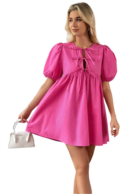 Bright pink puff sleeve mini dress with a tie-front detail, styled for a chic look, paired with a white handbag. Available at Catherine Martin store, Australia.