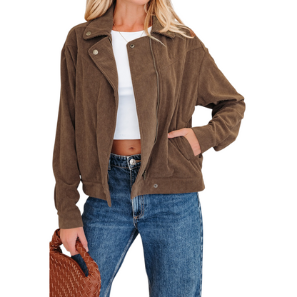 A woman wearing a brown corduroy zip-up jacket over a white crop top and blue jeans, highlighting the gold hardware and functional side pockets.