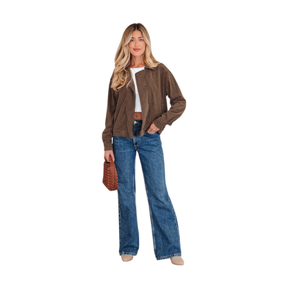 A woman wearing a brown corduroy zip-up jacket over a white crop top and blue jeans, highlighting the gold hardware and functional side pockets.