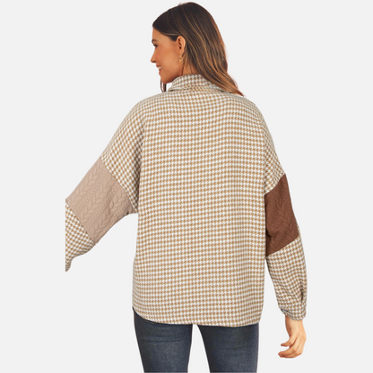 A model viewed from the back, displaying the distinctive brown patchwork shacket with a mix of houndstooth pattern and different-coloured cable-knit sleeves.