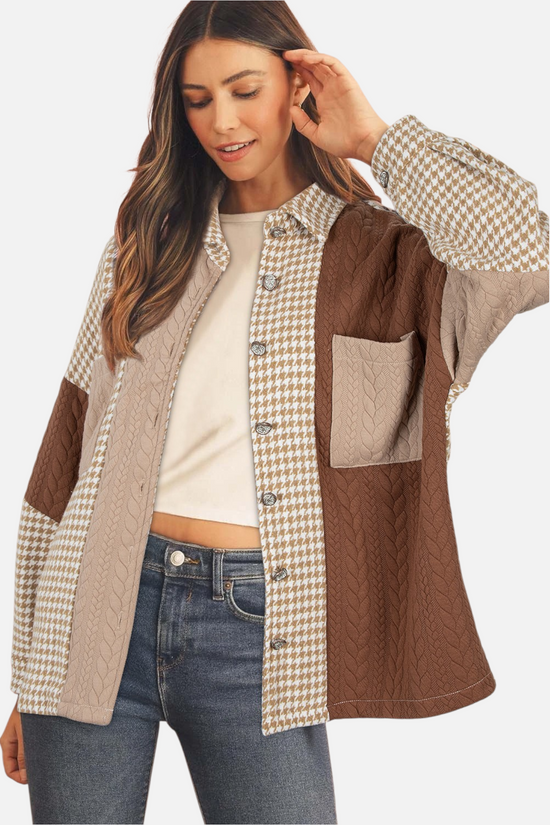 A model styled in a brown patchwork shacket with houndstooth and cable-knit textures, layered over a white top and blue jeans, looking down with a smile.