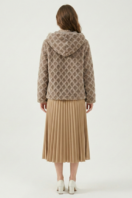 Person wearing a patterned jacket and beige pleated skirt on a white background