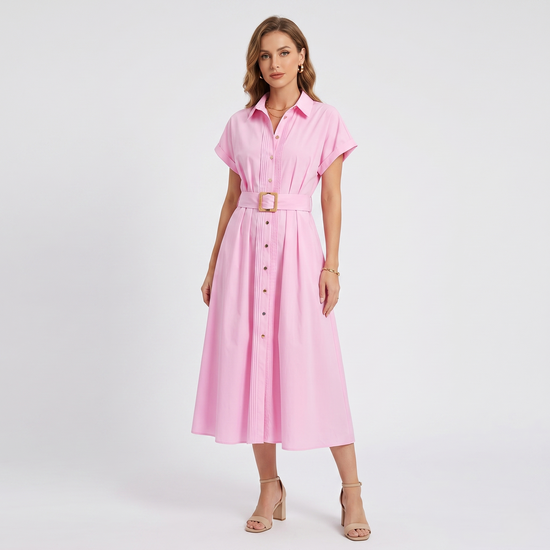 A full front view of a model wearing a bubblegum pink long shirt dress featuring a collared neckline, short sleeves, and a matching belt with a woven straw buckle.