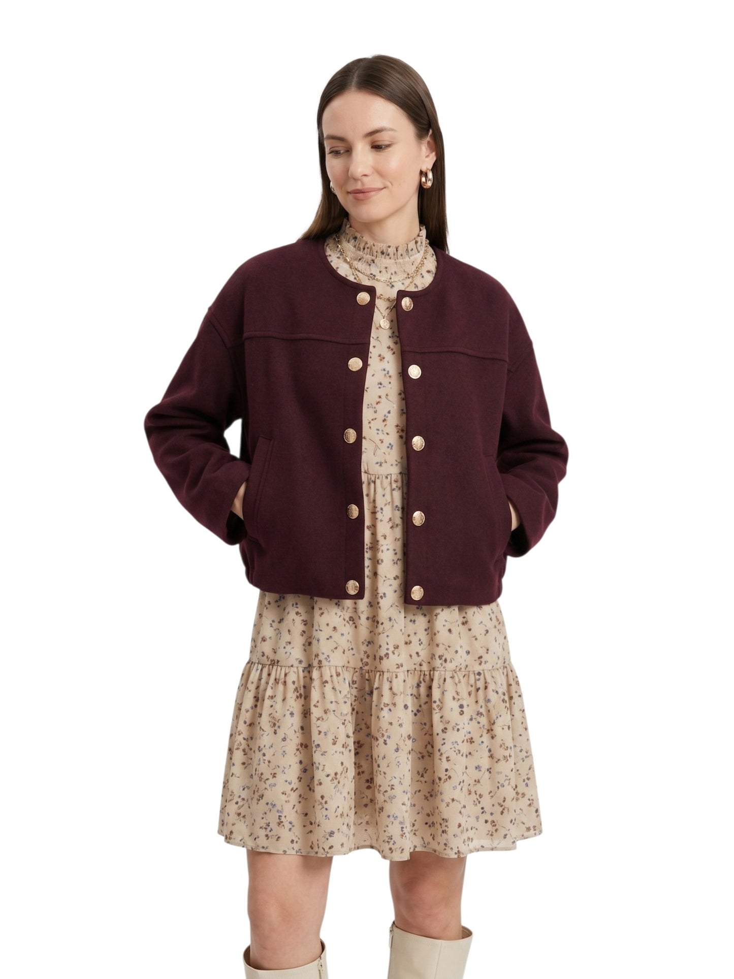 Woman wearing a burgundy jacket over a floral dress on a white background