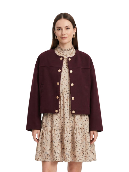Close-up front view of the model wearing the wine red cropped button-up jacket, showcasing the round neck and gold crest buttons.