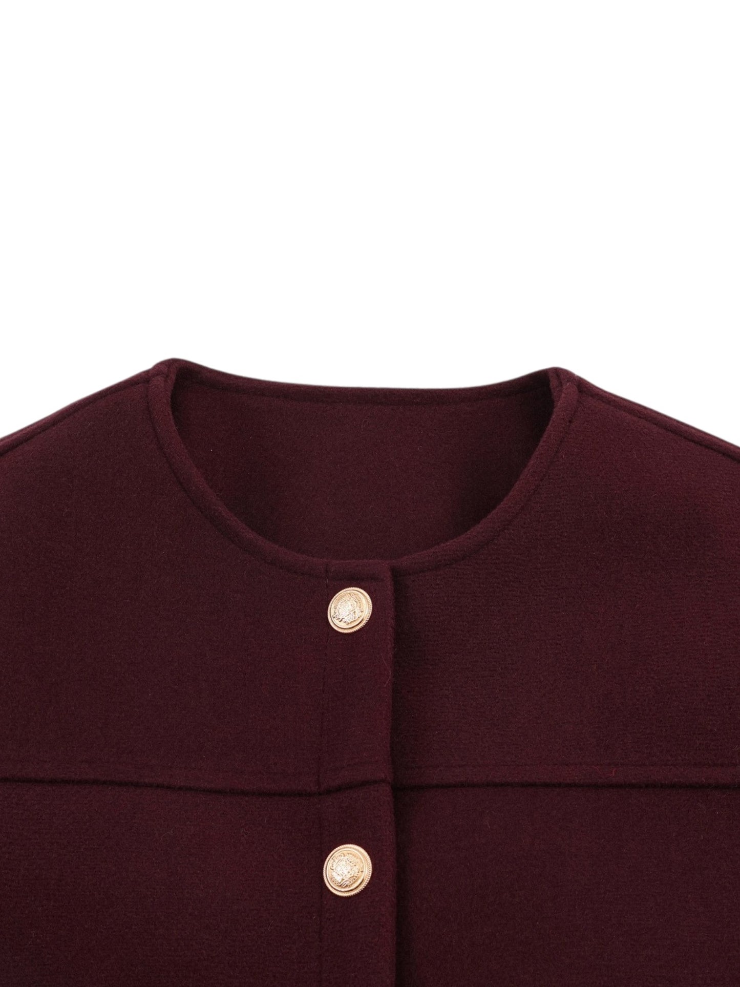 Macro studio shot highlighting the textured collarless neckline, horizontal chest yolk seam, and embossed gold metallic buttons.