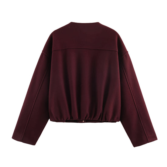The rear view of the burgundy jacket highlighting the sculptural gathered elastic hem for a flattering, cinched silhouette.