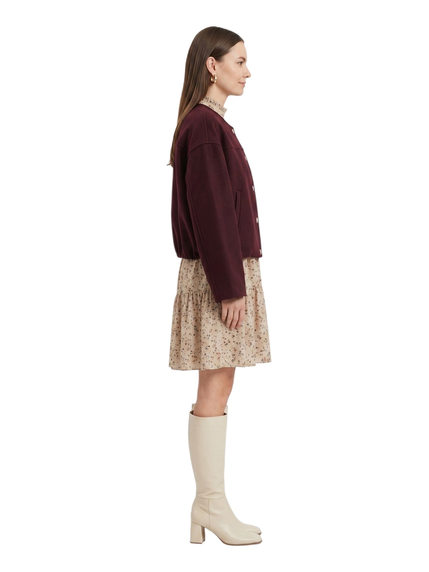 Woman wearing a burgundy sweater and beige skirt with white boots on a white background