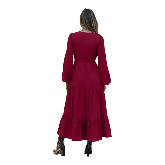 Woman in a burgundy, long-sleeve, tiered maxi dress with a V-neckline and drawstring waist, paired with black ankle boots