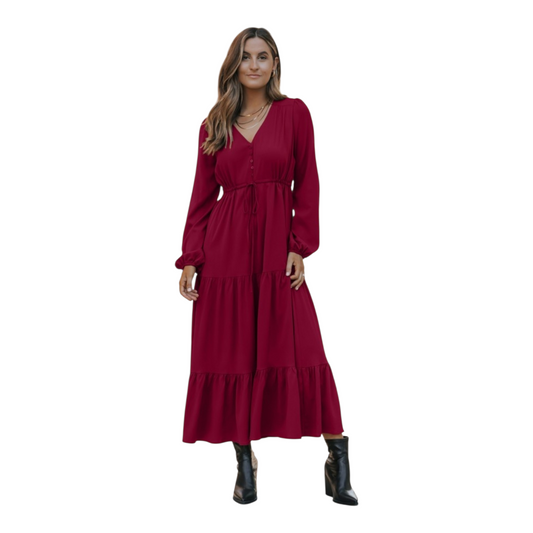 Woman in a burgundy, long-sleeve, tiered maxi dress with a V-neckline and drawstring waist, paired with black ankle boots