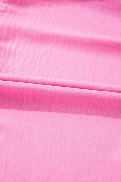 Close-up of a lightweight pink dress with a halter neckline and soft ruffles.
