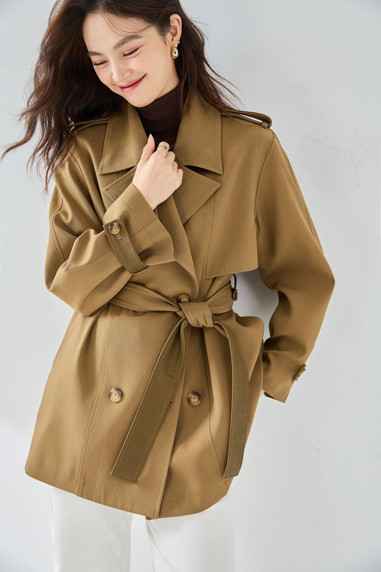 Woman wearing a brown trench coat against a white background