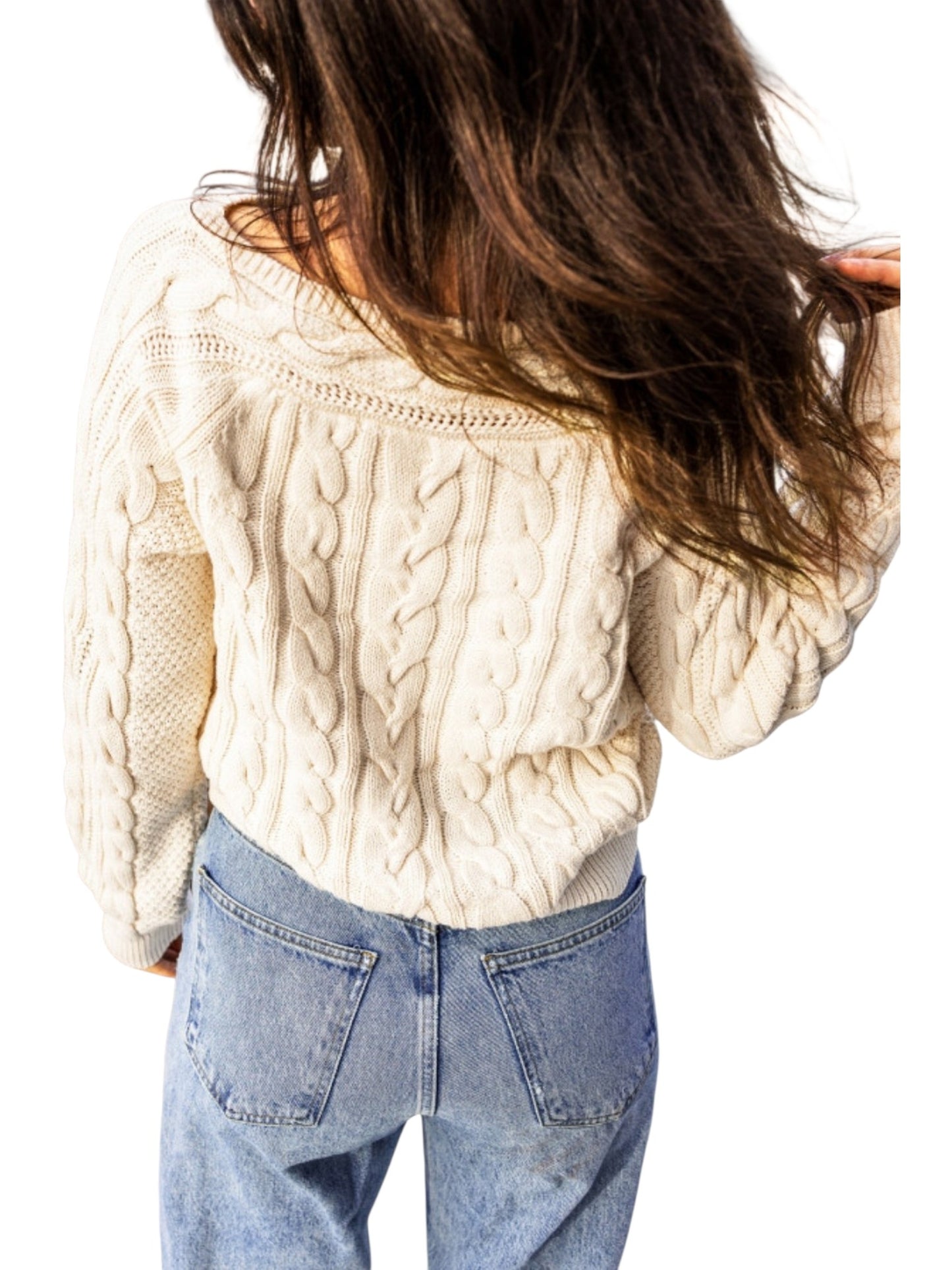 A woman shown from behind wearing a cream cable-knit sweater and light blue jeans against a plain white background.