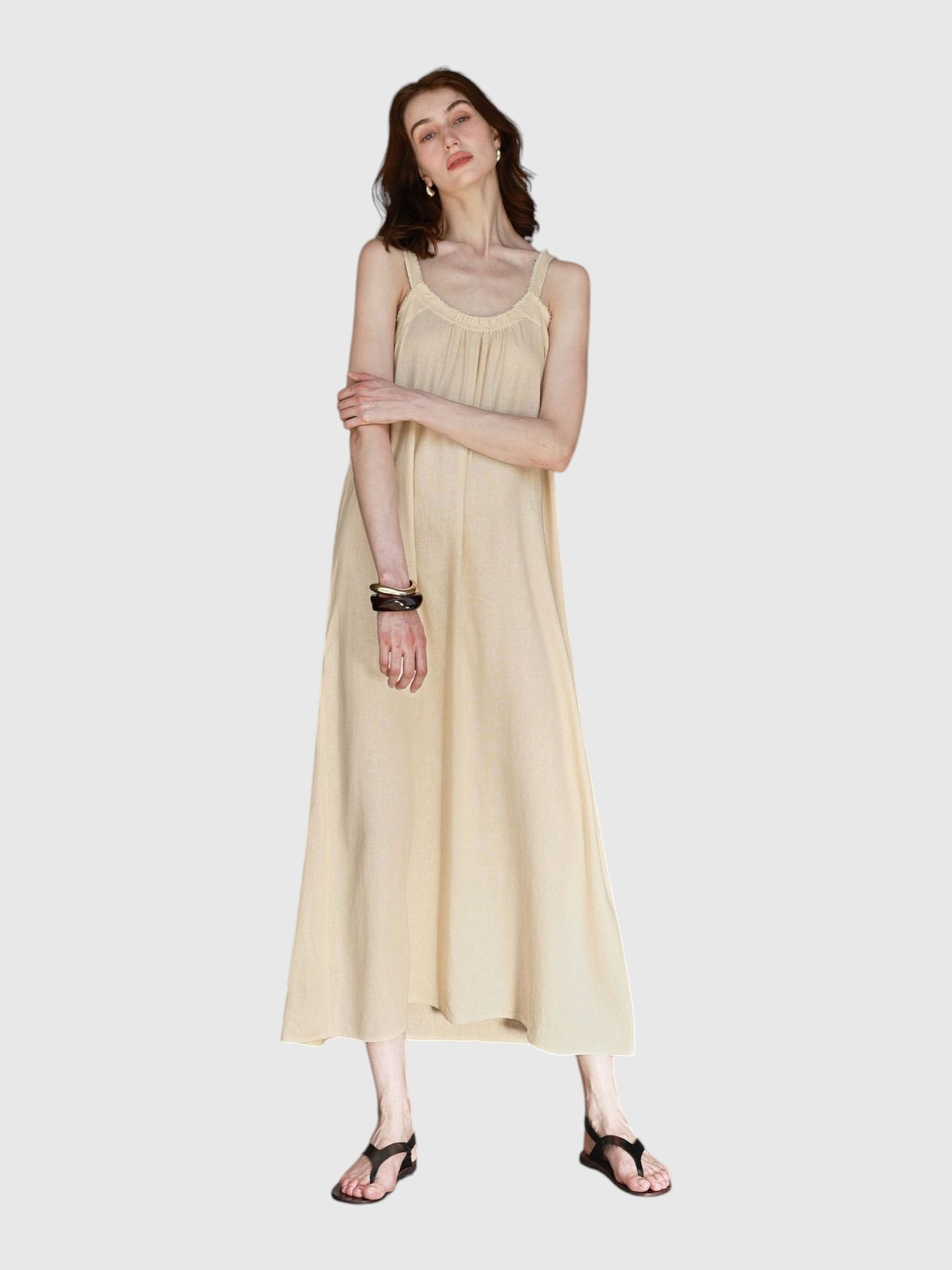 Model wearing a Catherine Martin beige linen and cotton maxi dress with frayed raw edges and a scoop neckline.