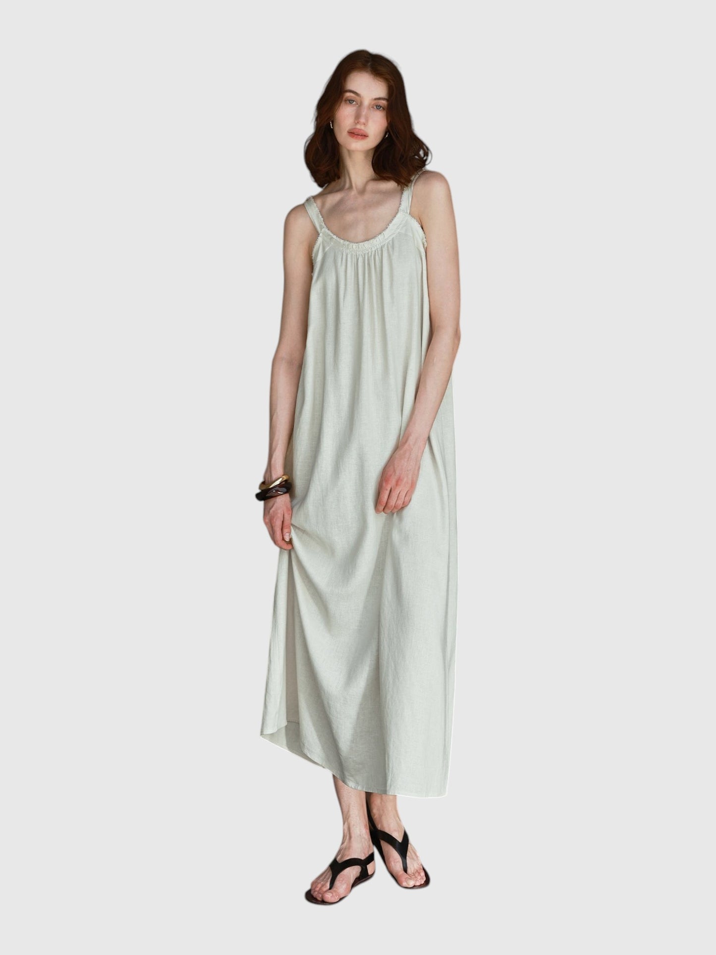 Model wearing a Catherine Martin cream linen and cotton maxi dress with frayed raw edges and a scoop neckline.
