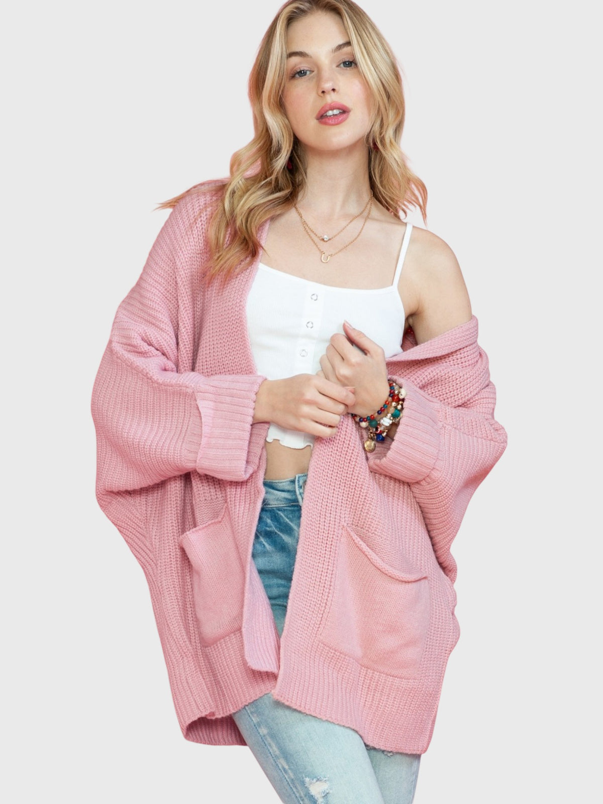 Model wearing a Catherine Martin dusty pink oversized open front knit cardigan with patch pockets and ribbed cuffs.