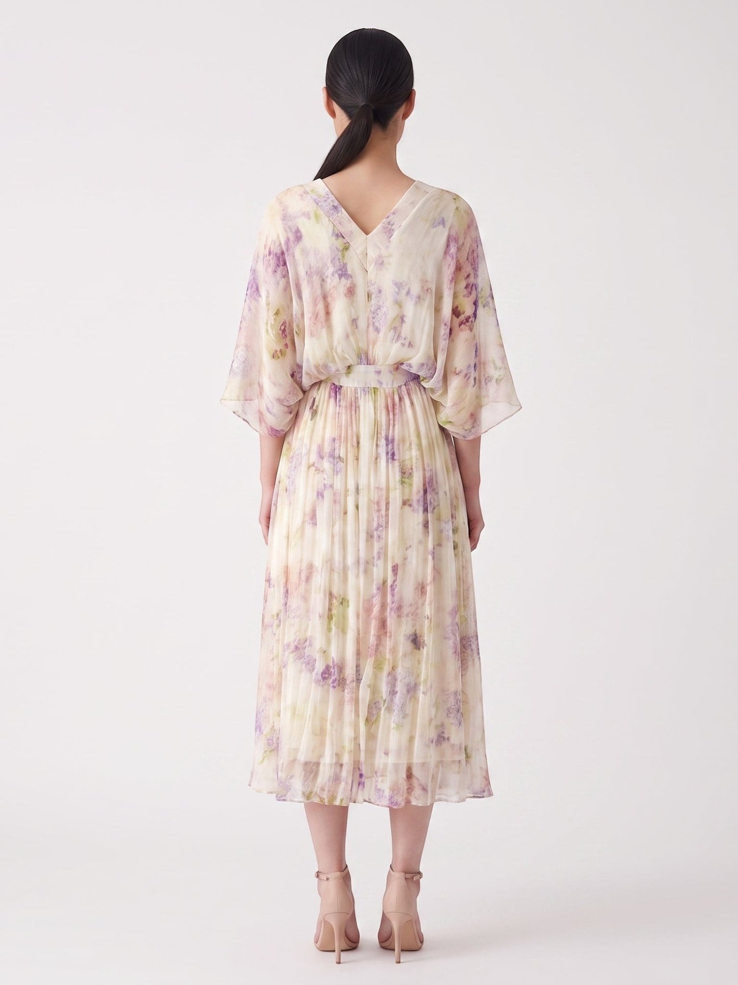Back view of a Catherine Martin floral silk midi dress with kimono sleeves and a pleated skirt in lilac and cream.