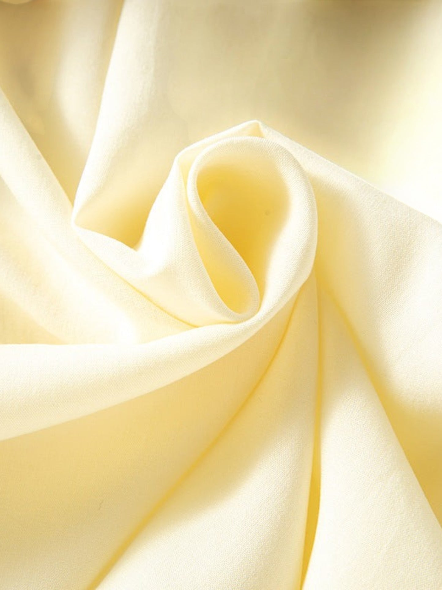 Catherine Martin silk chiffon fabric in a soft pale yellow with delicate folds and a smooth, airy texture.