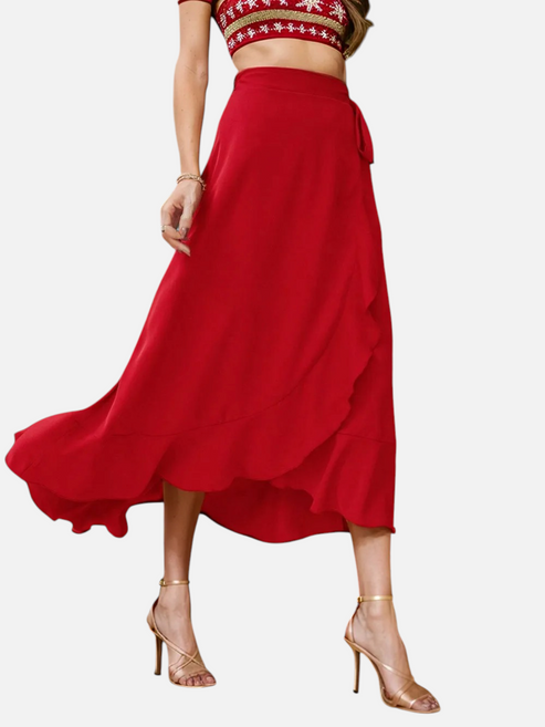 Catherine Martin red midi wrap skirt with ruffle trim and asymmetric hem worn with gold heels in a festive setting