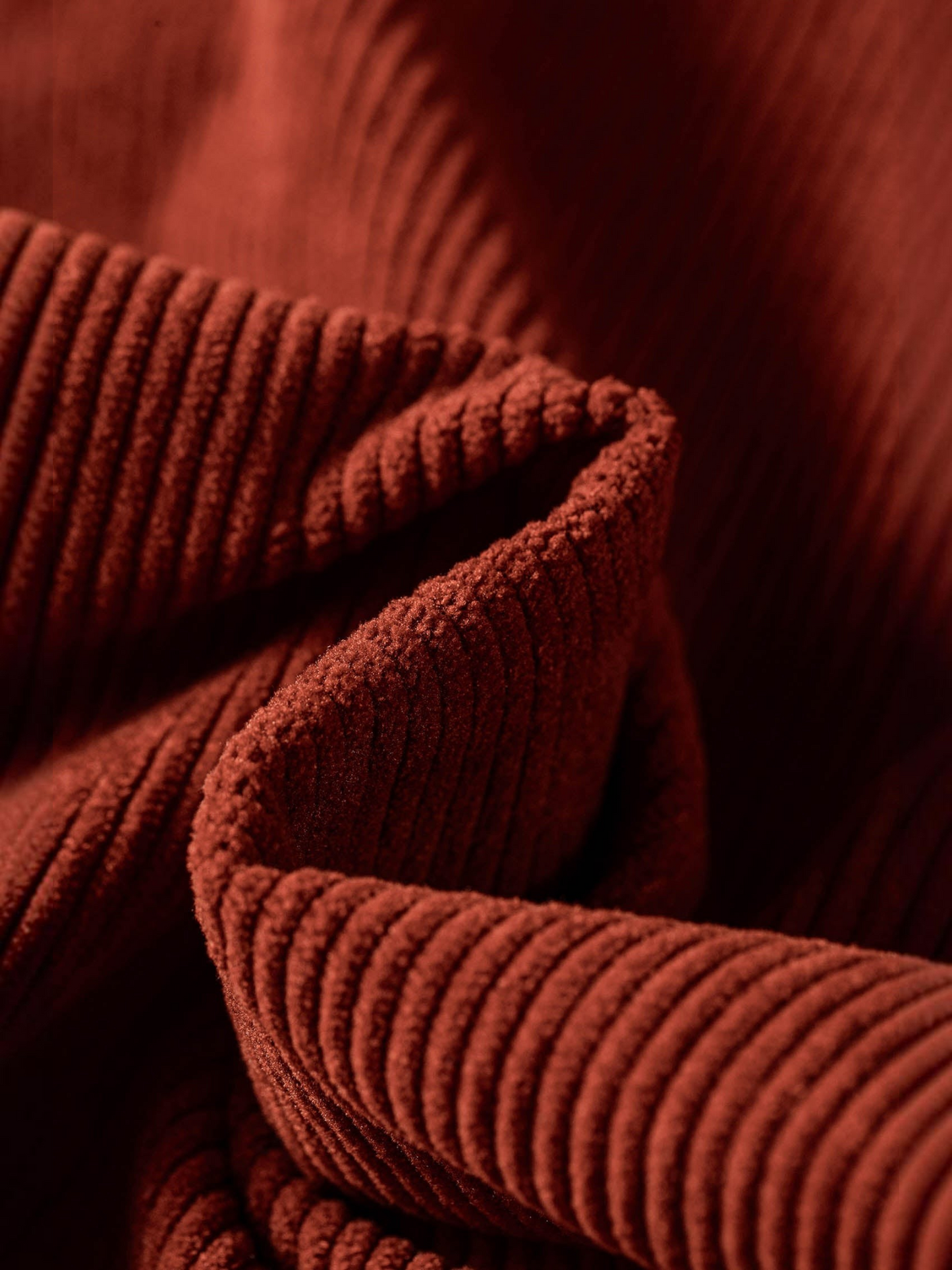 Close-up of Catherine Martin rust-coloured polyester corduroy fabric showing soft ribbed texture and deep folds
