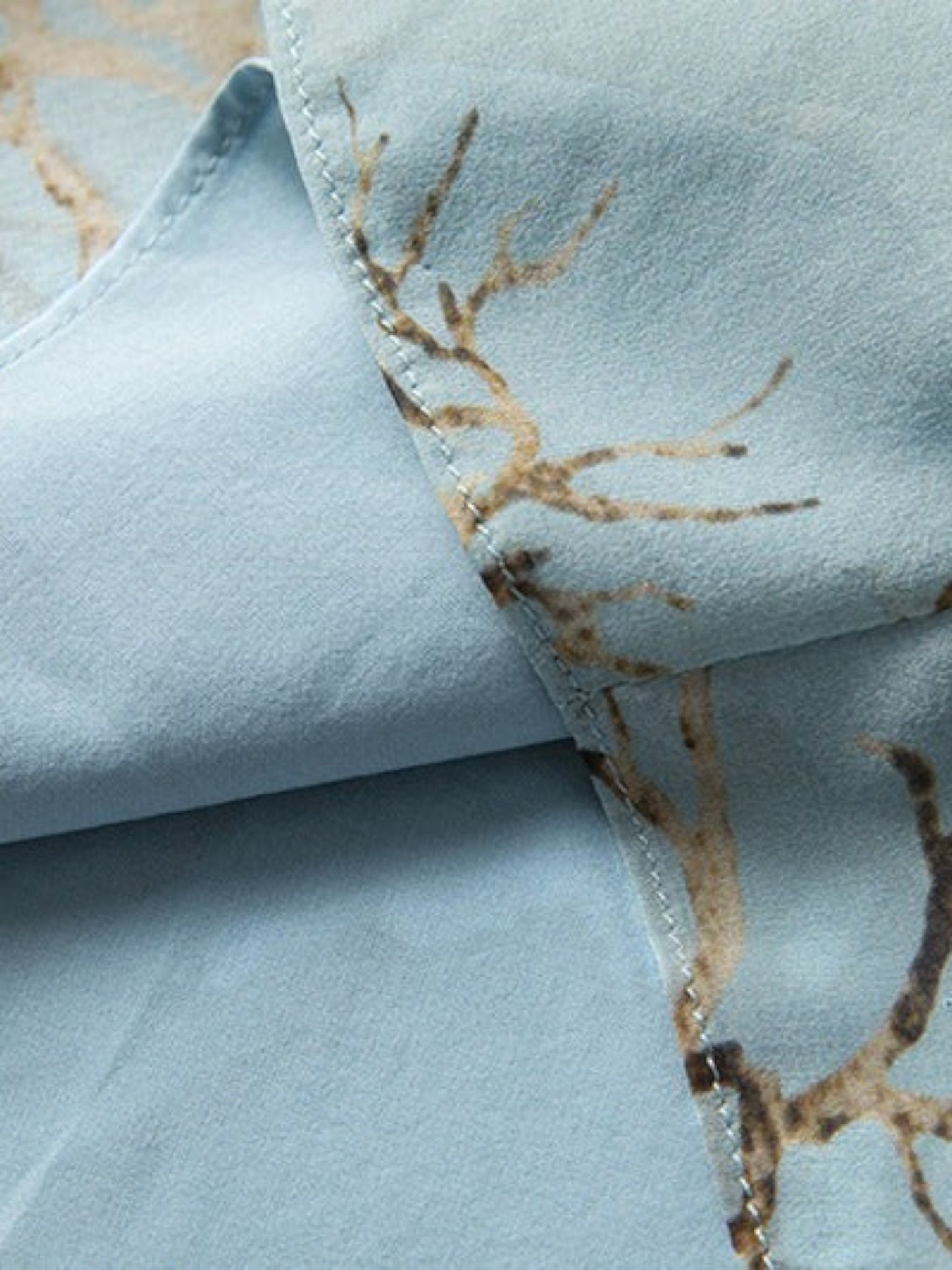 Close-up of Catherine Martin powder blue mulberry silk dress with gold and brown branch print and interior lining