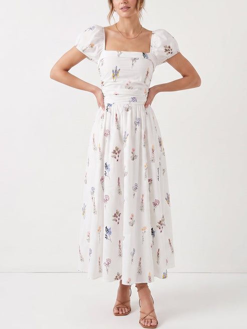 Catherine Martin white cotton midi dress with wildflower print, square neckline, puff sleeves, and smocked bodice.
