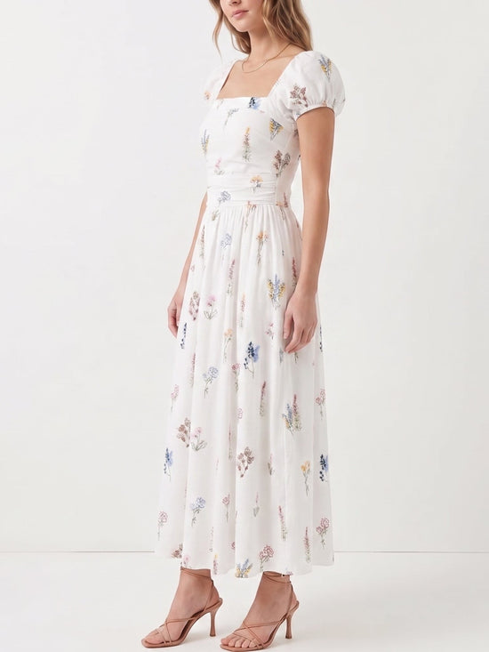 Catherine Martin white cotton midi dress with wildflower print, square neckline, puff sleeves, and smocked bodice.