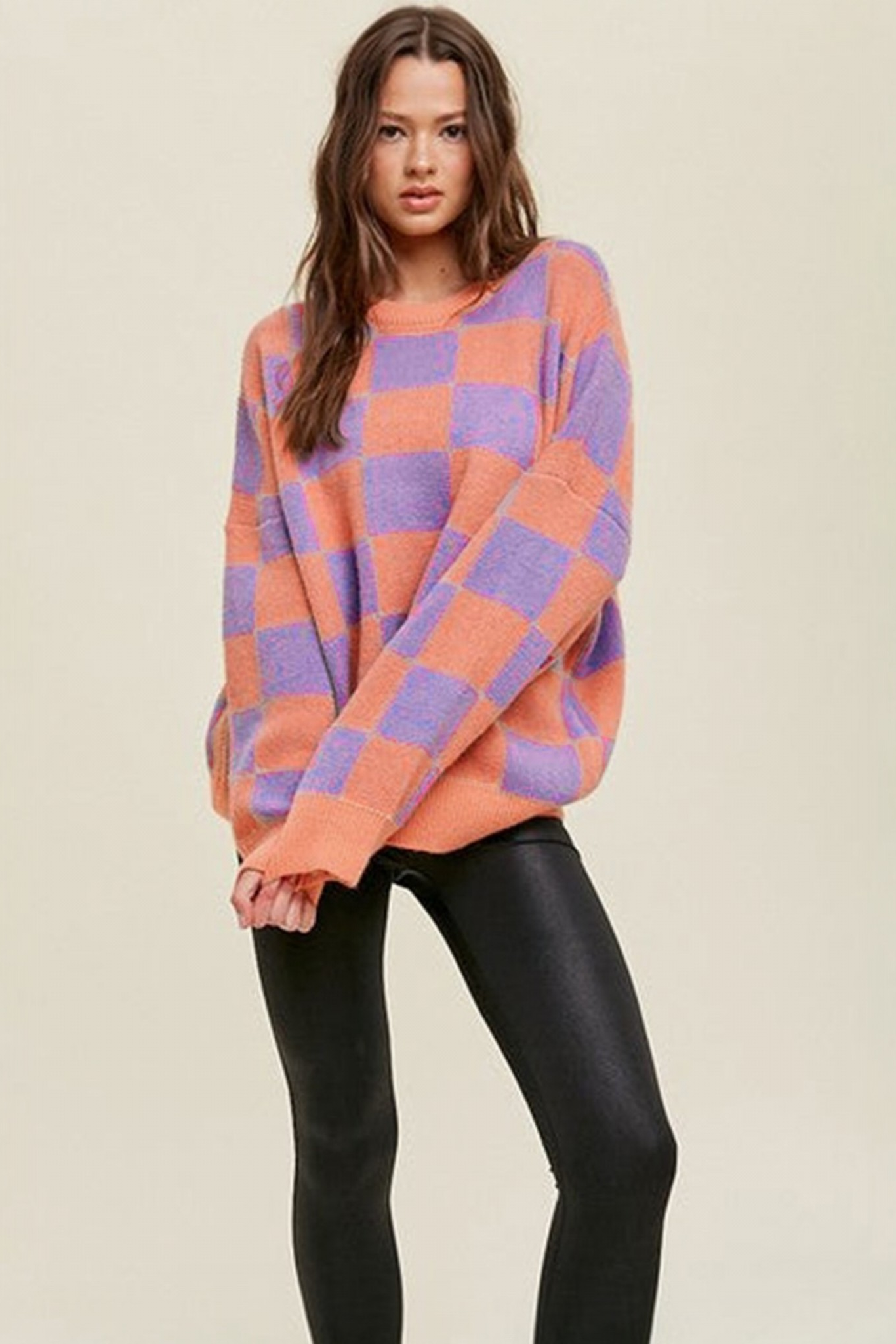 Coral checkerboard crew neck knit sweater front full length view styled with black leather-look pants