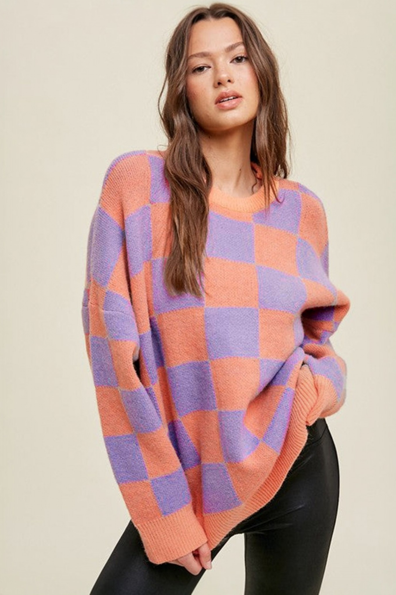 Coral checkerboard crew neck knit sweater front view showing large-scale coral and lilac check pattern and crew neckline