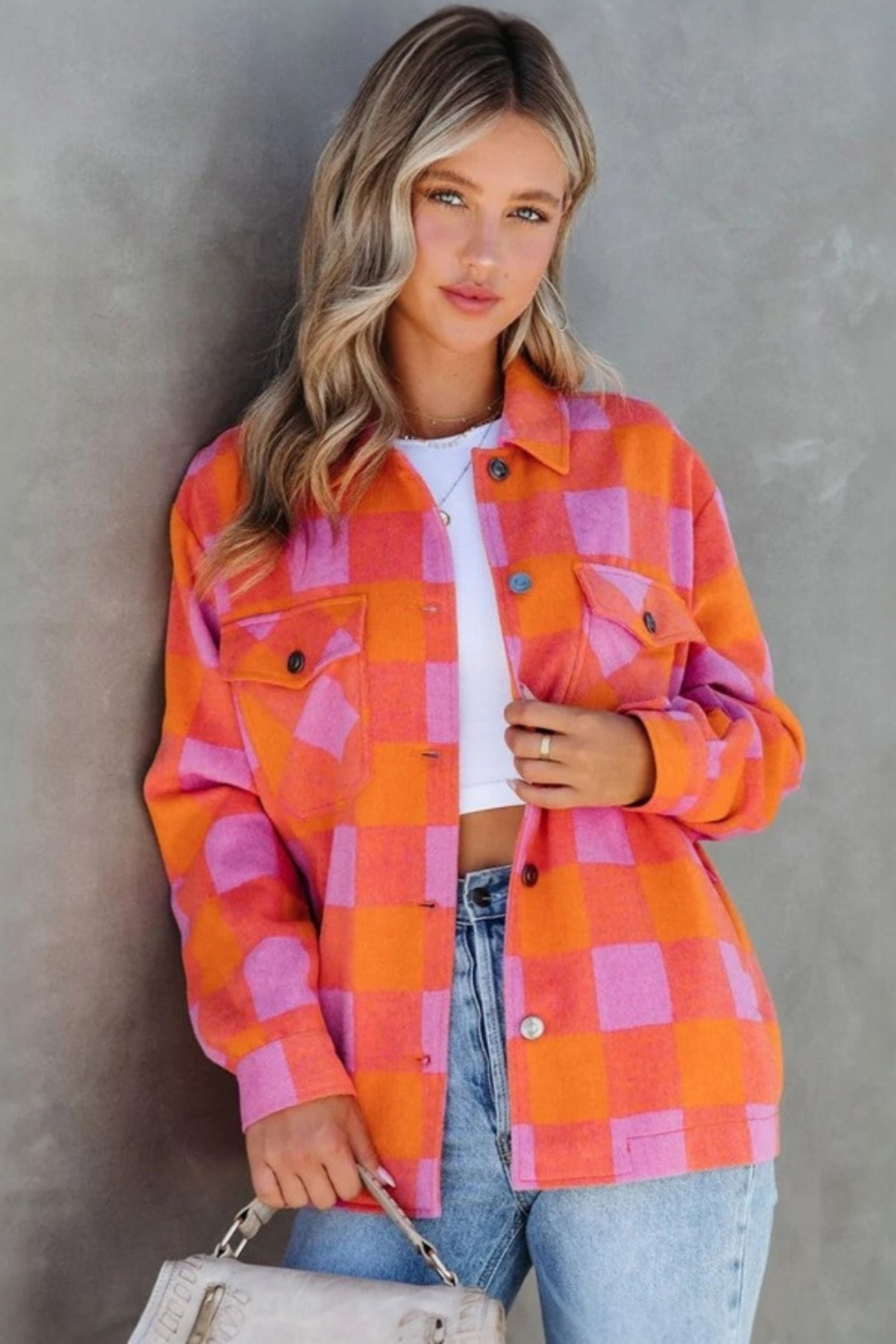 Lifestyle portrait of a model in the pink and orange plaid shacket, styled as a lightweight outer layer for a casual, trendy aesthetic.