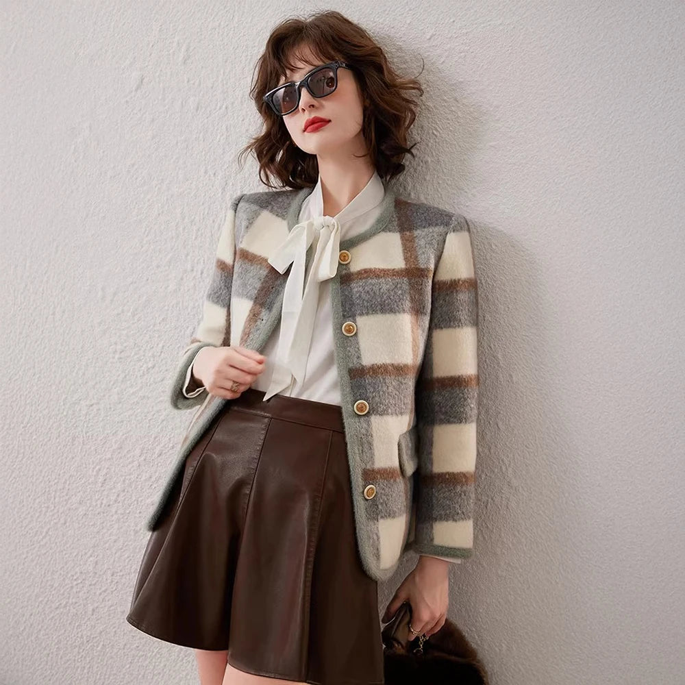 Woman wearing a plaid jacket and brown skirt against a white wall