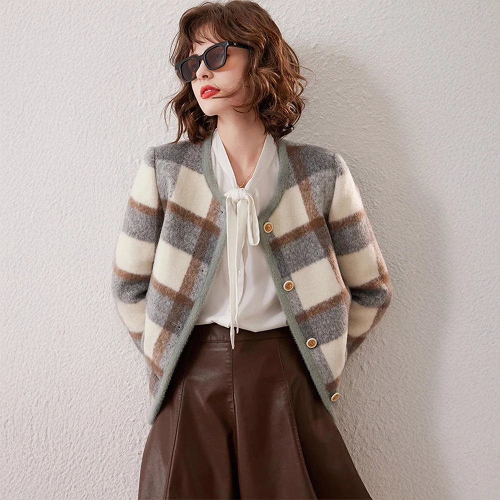 Woman wearing a plaid cardigan, white blouse, and brown leather skirt against a light background