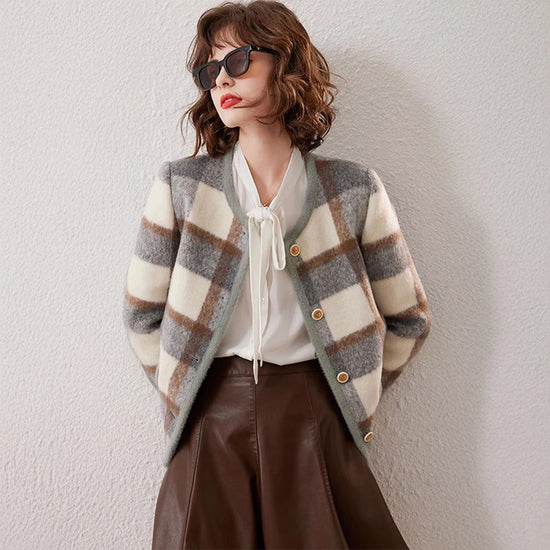 Woman wearing a plaid cardigan, white blouse, and brown leather skirt against a light background
