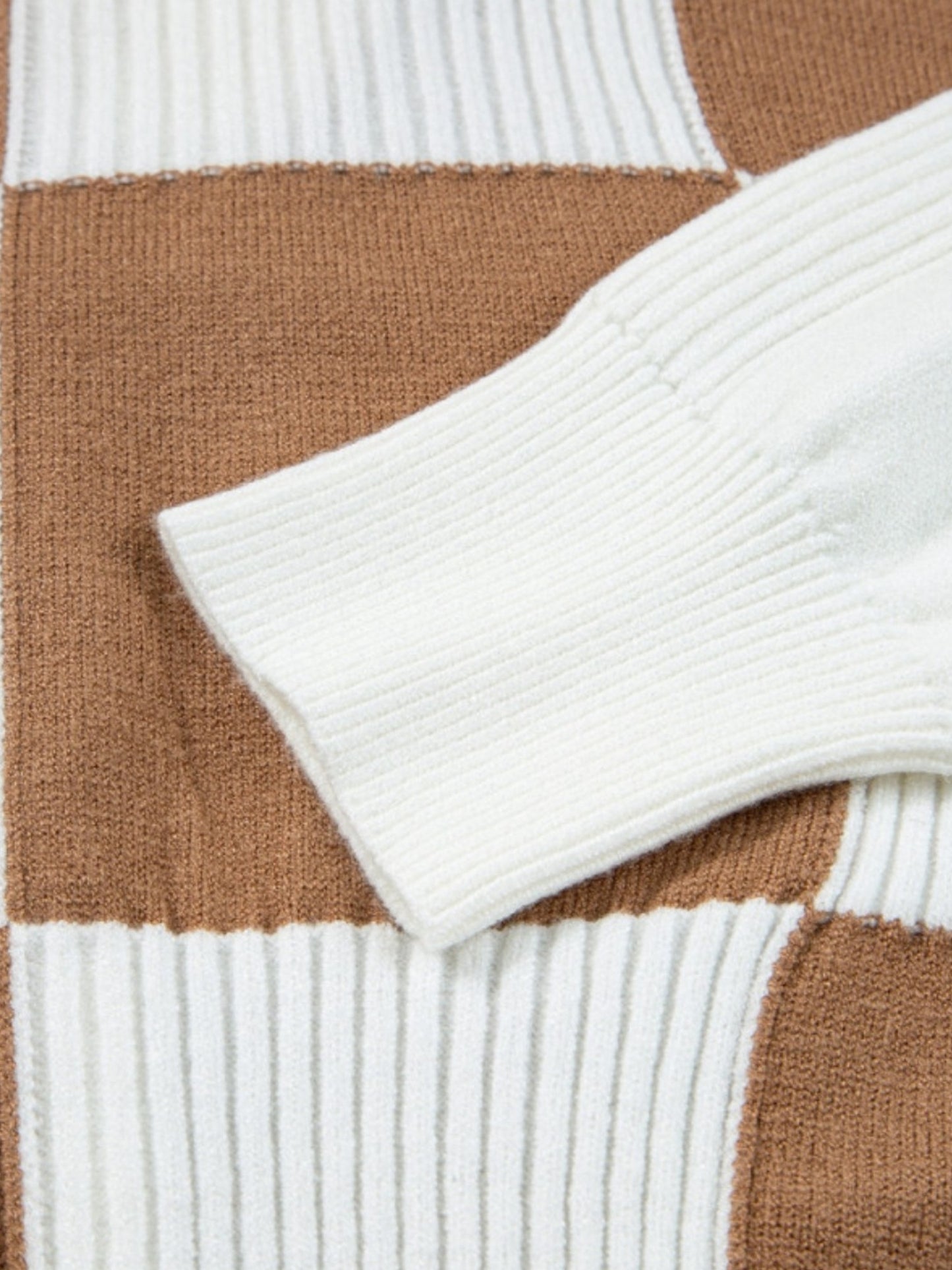 Close-up of a ribbed knit sweater with alternating white and warm brown check blocks.