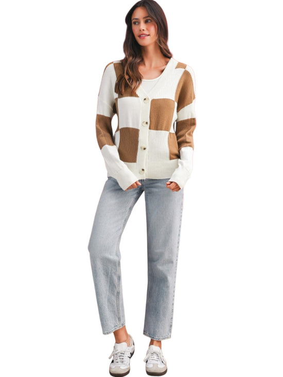 A woman modeling a color-block knit cardigan sweater with light-wash jeans and white sneakers against a plain white background.